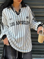 Person wearing a 'Los Angeles' striped shirt holding a drink.