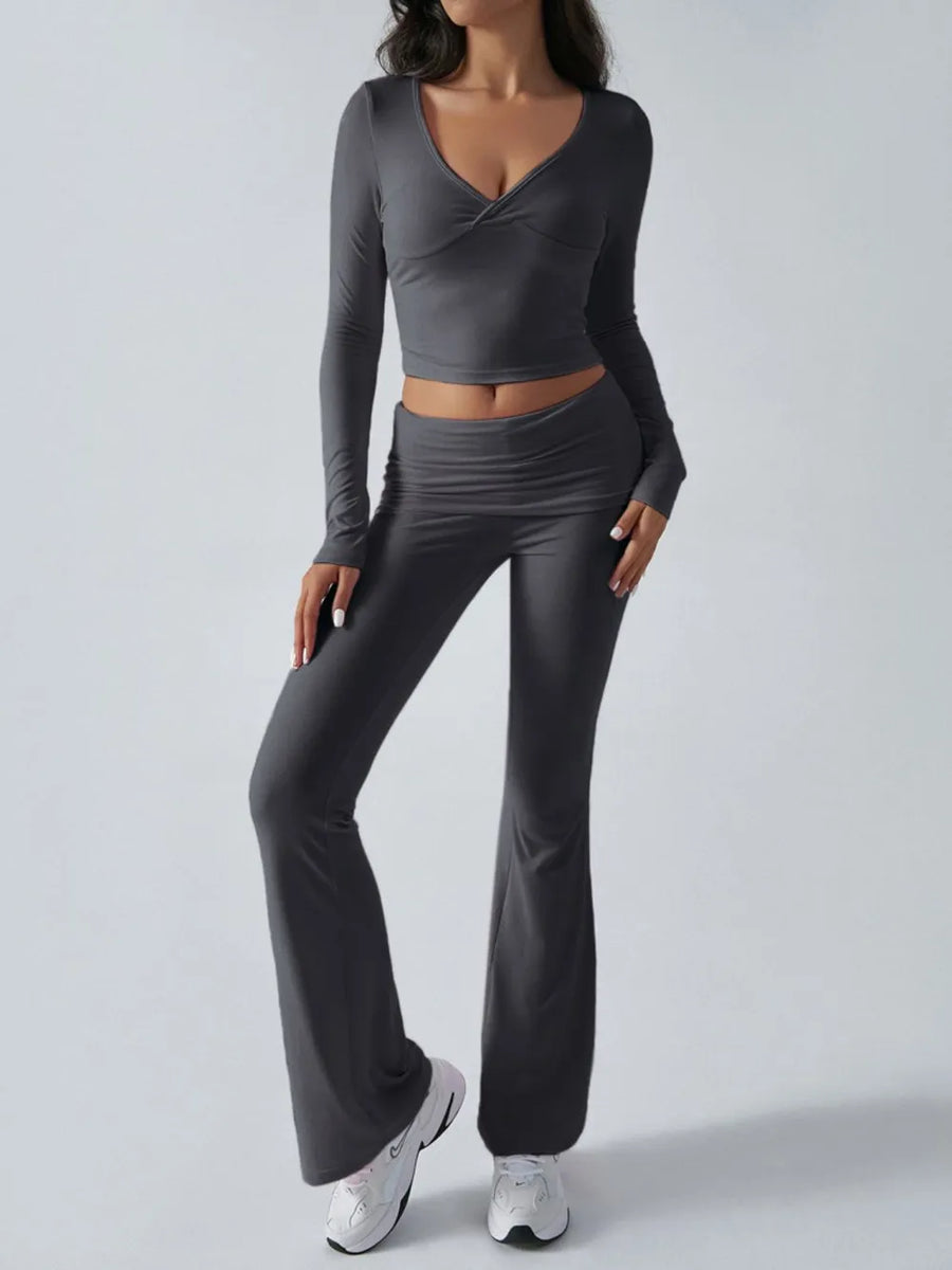 Person wearing a gray long-sleeve crop top and flared pants on a light gray background