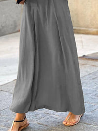 Gray wide-leg pants worn by a person on a stone pavement.
