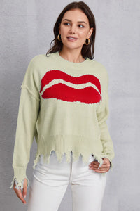 Woman wearing a light green sweater with a red graphic design on a gray background