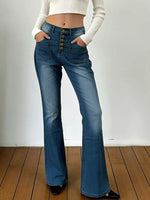 Person wearing blue flared jeans with button details on a wooden floor.