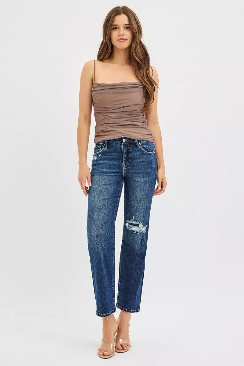 Woman wearing a brown top and blue jeans on a white background