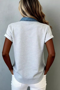 Person wearing a light gray short-sleeve shirt and white pants against a plain background