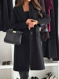 Person wearing a black coat with a handbag in a clothing store setting