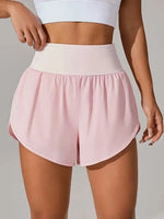 Person wearing pink athletic shorts and a white top on a plain background