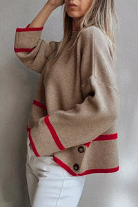 Beige sweater with red accents worn by a person against a neutral background