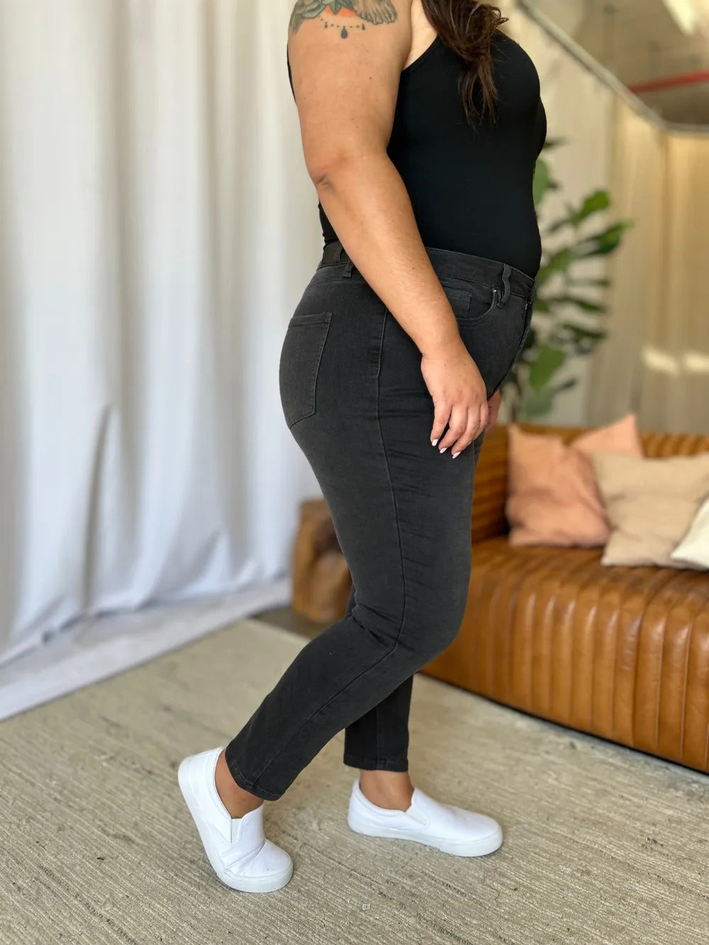 Person wearing black jeans and a black top in a living room setting