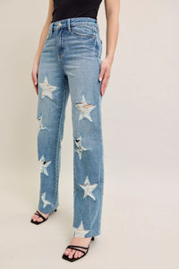 Blue jeans with star patterns worn by a person on a plain background