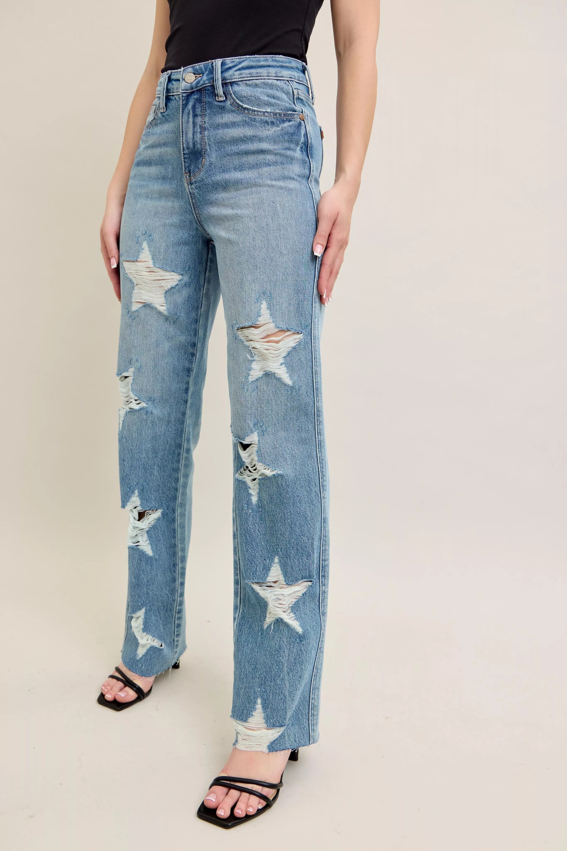 Blue jeans with star patterns worn by a person on a plain background