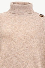 Close-up of a beige turtleneck sweater with a button on a white background