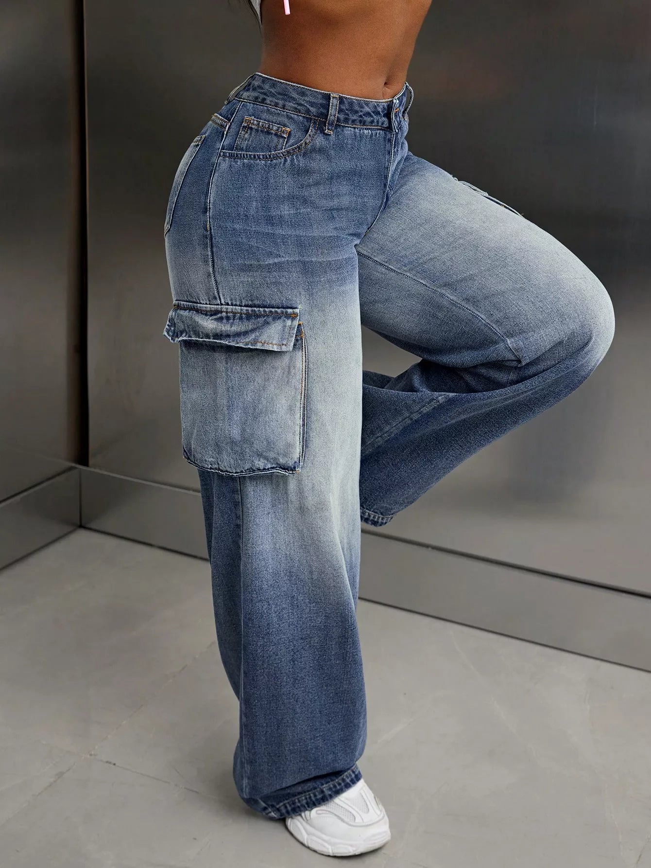 Person wearing high-waisted blue jeans with cargo pockets against a neutral background
