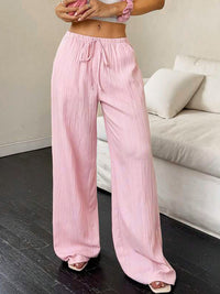 Person wearing pink wide-leg pants in a living room setting