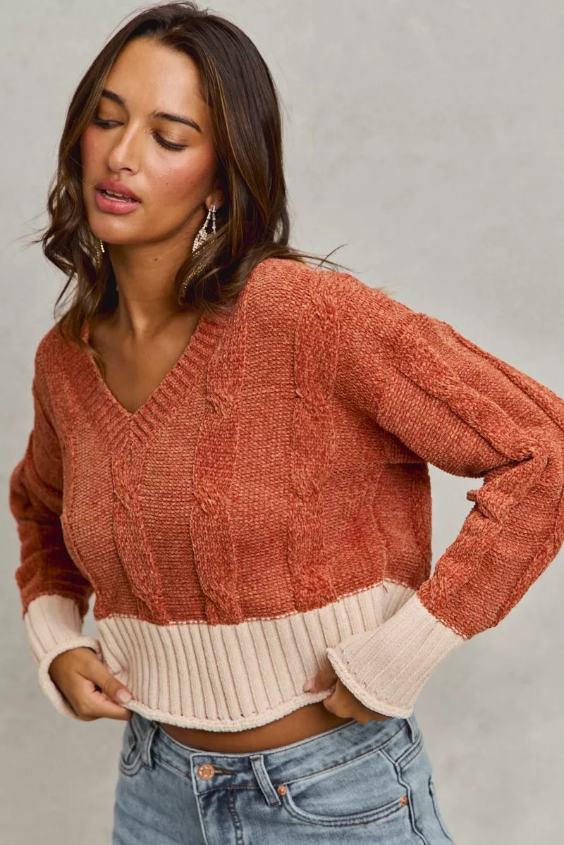 Woman wearing a two-tone sweater with a neutral background
