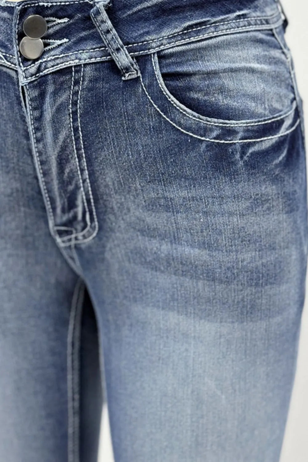 Close-up of blue jeans with a focus on the waistband and front pocket.