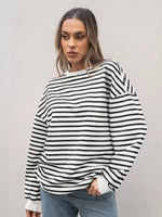 Woman wearing a black and white striped sweater against a plain background