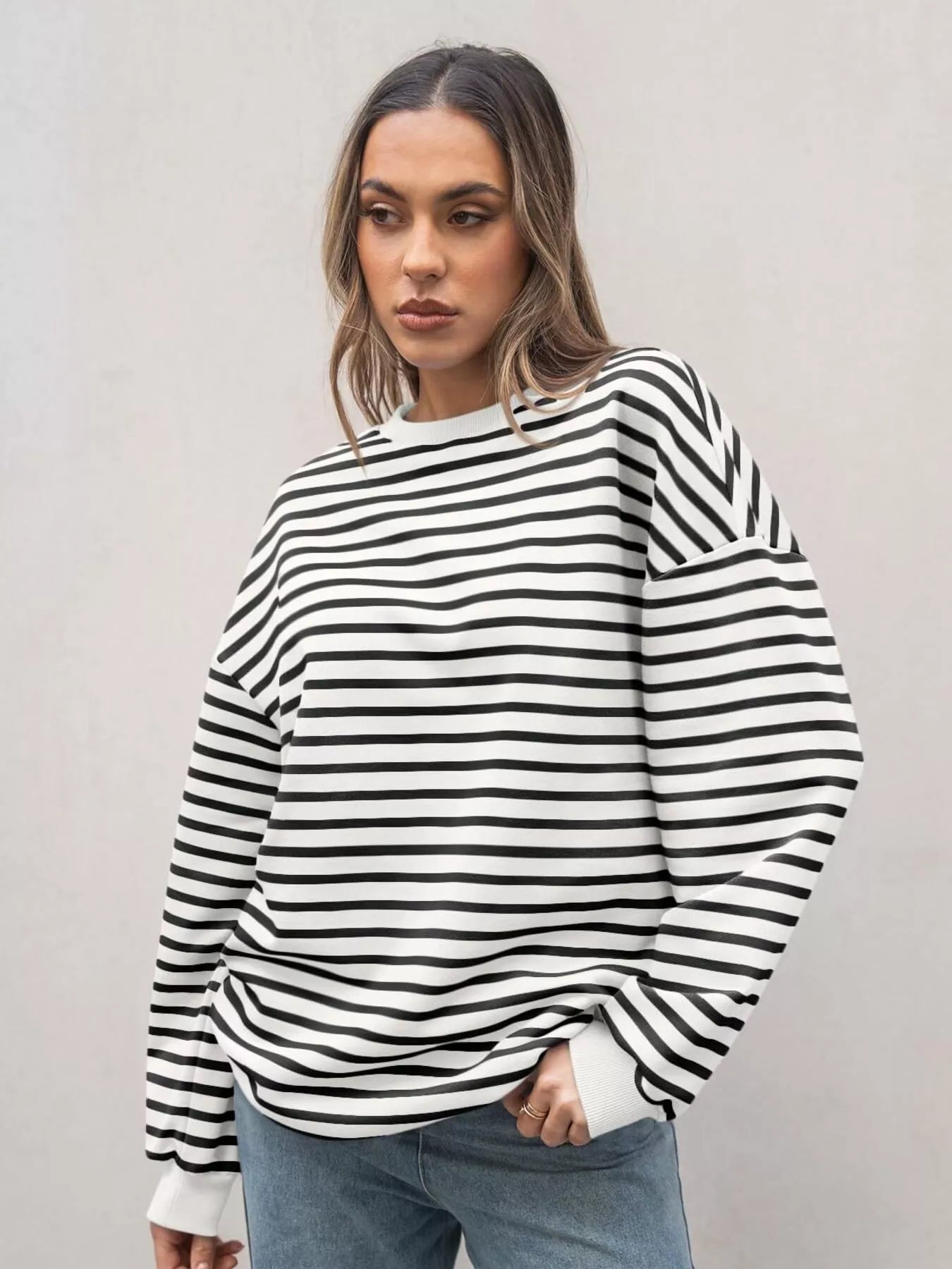 Woman wearing a black and white striped sweater against a plain background
