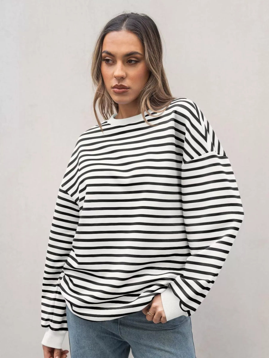 Woman wearing a black and white striped sweater against a plain background