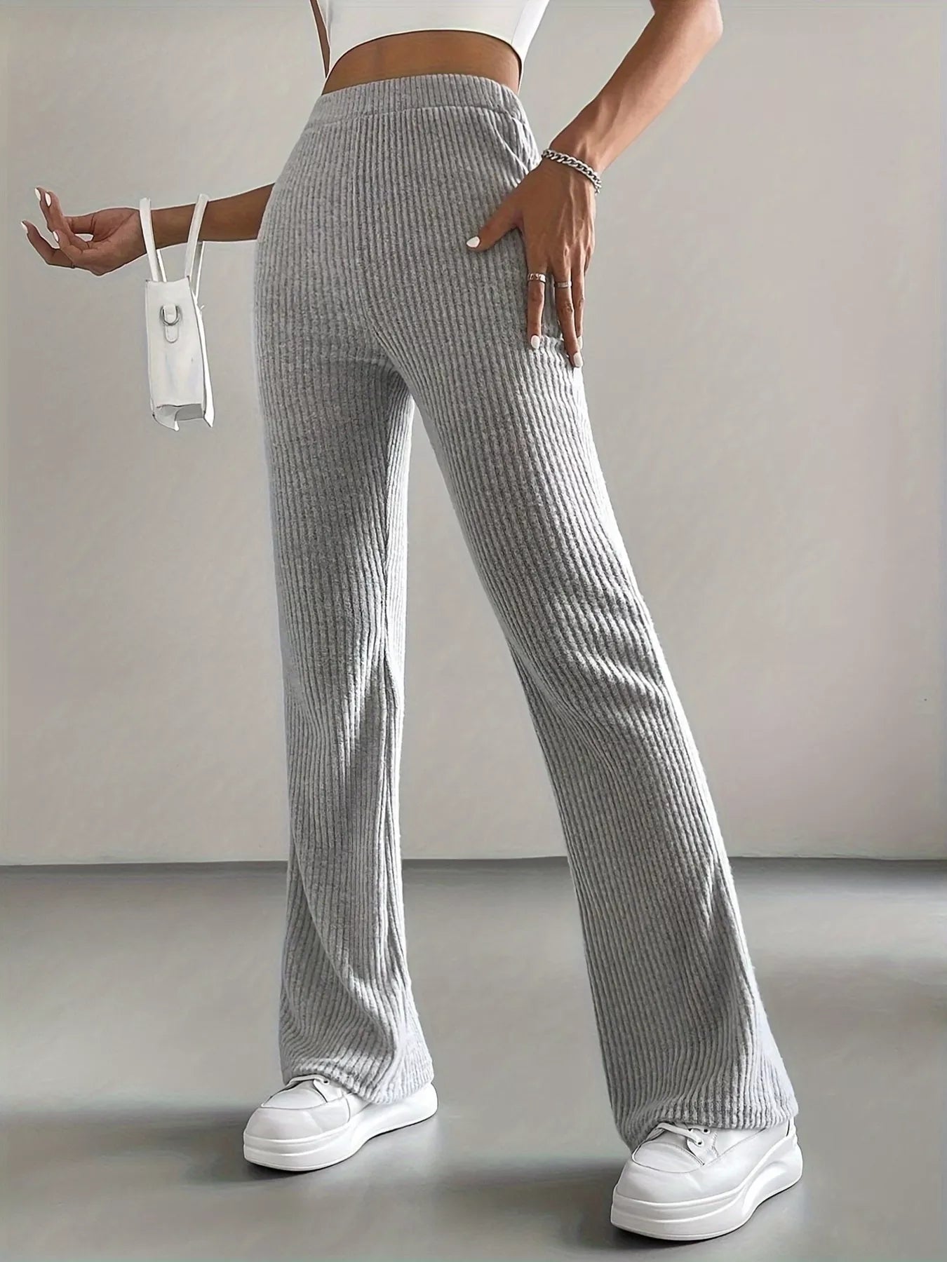 Person wearing gray ribbed pants and white sneakers on a plain background