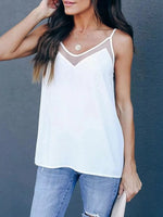 Woman wearing a white tank top and blue jeans against a gray background