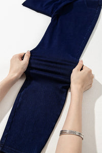 Navy blue fabric being held by hands on a light background
