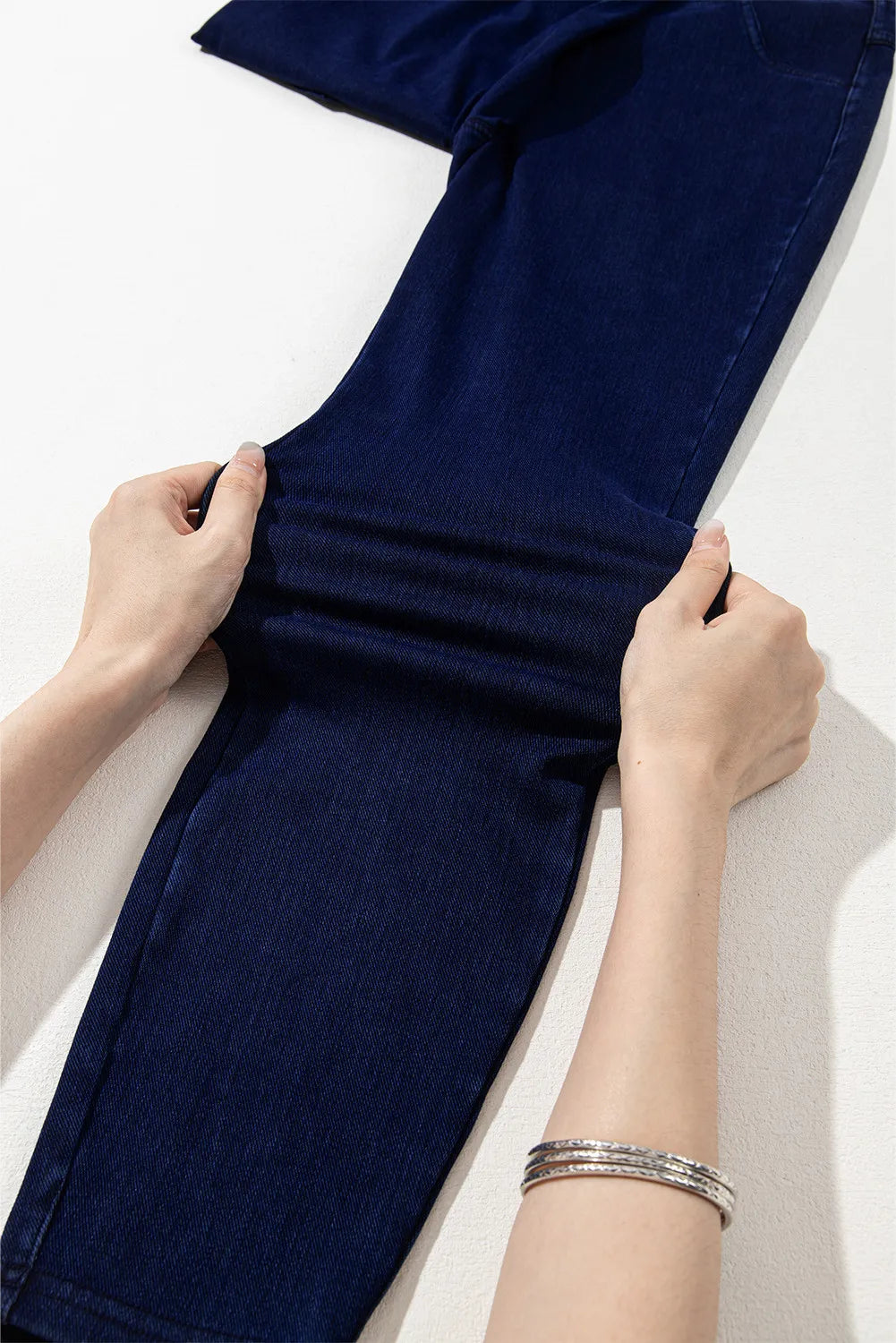 Navy blue fabric being held by hands on a light background