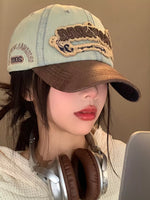 Person wearing a denim cap with embroidery and headphones, against a neutral background