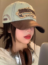 Person wearing a denim cap with embroidery and headphones, against a neutral background