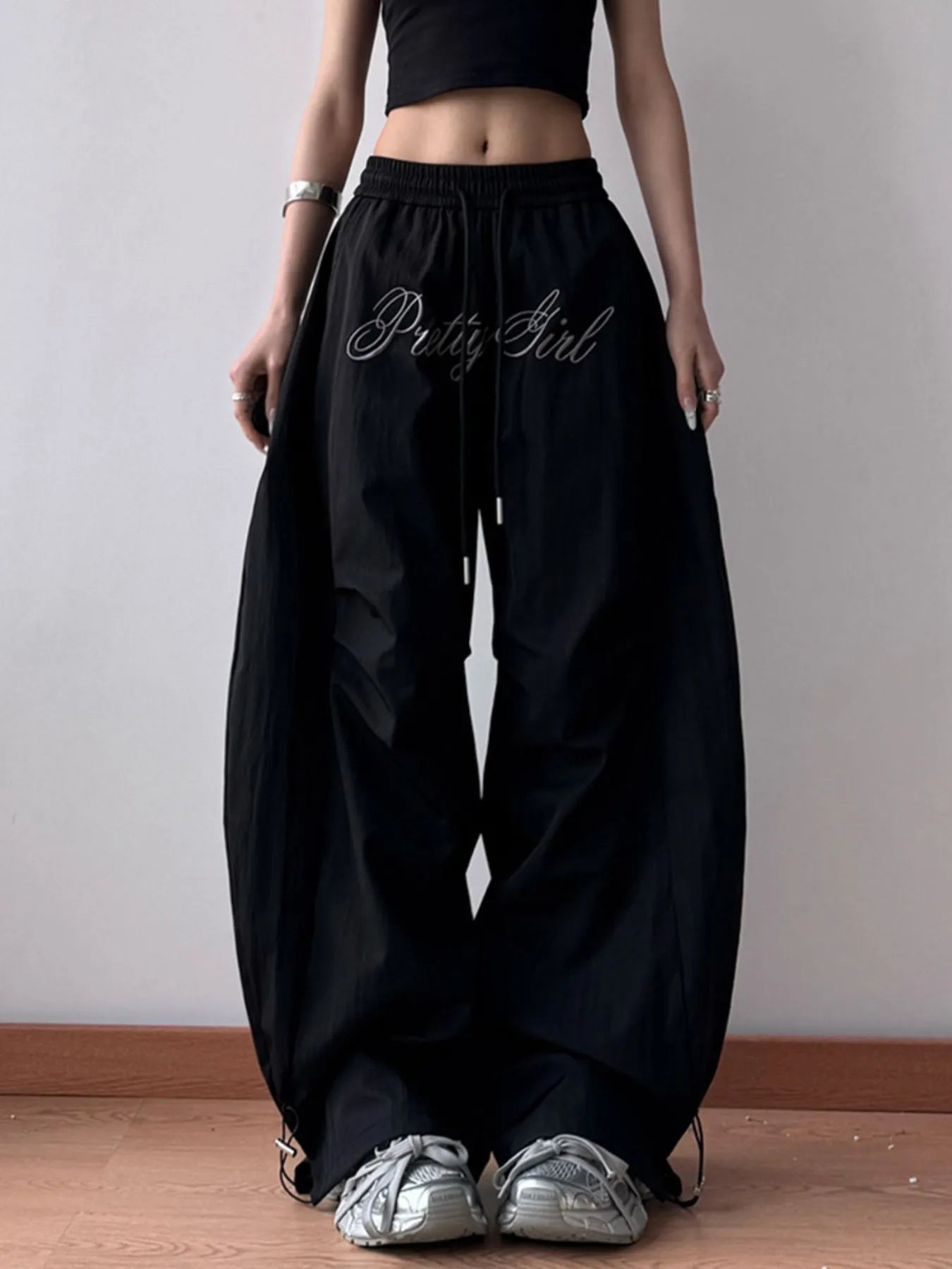 Person wearing black wide-leg pants with 'Pitty Girl' text, standing against a plain background.