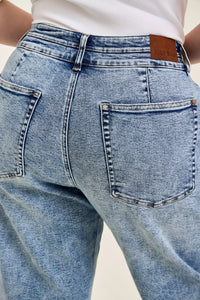 Close-up of blue jeans with a brand label on a neutral background
