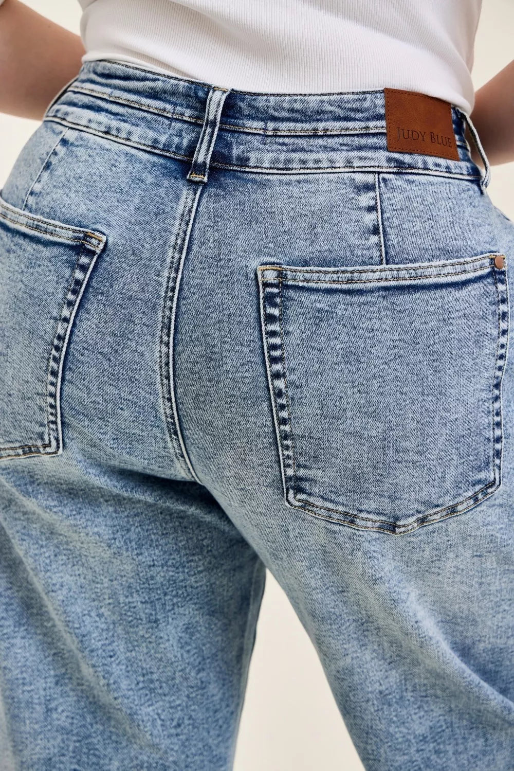 Close-up of blue jeans with a brand label on a neutral background