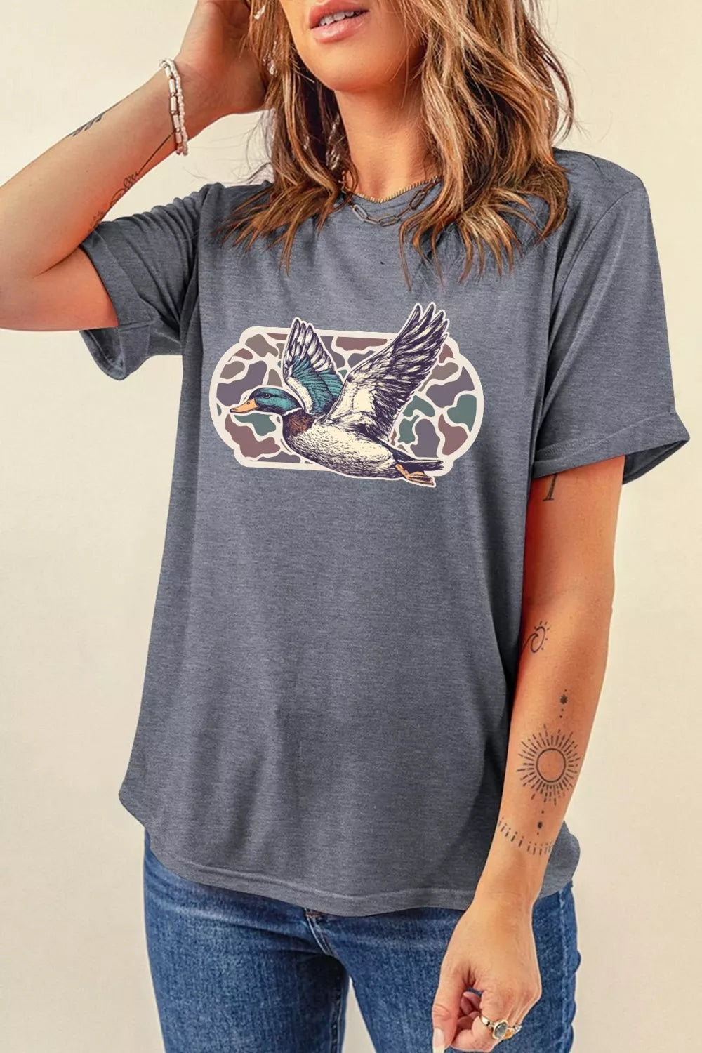 Person wearing a gray t-shirt with a duck graphic design on a beige background
