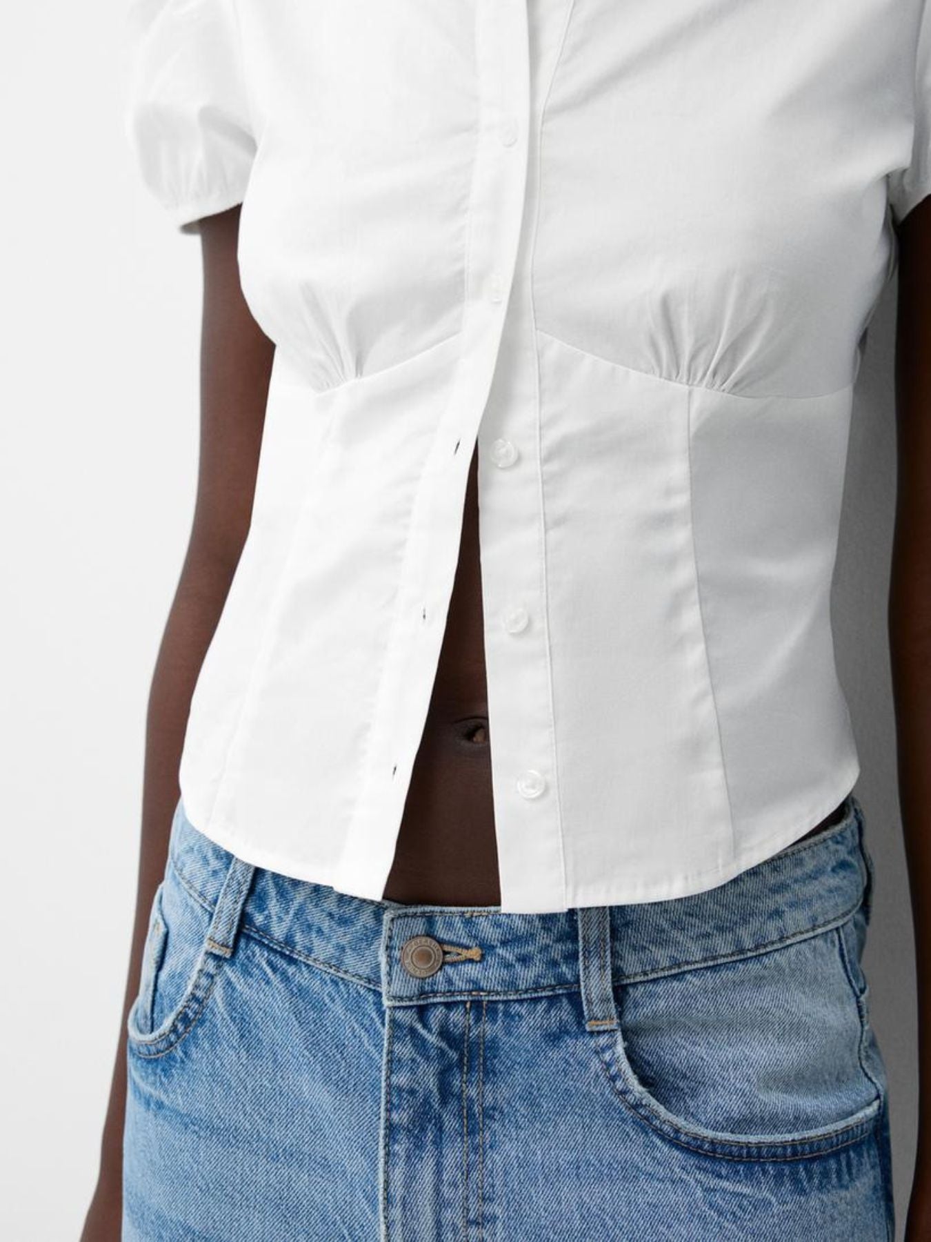 White shirt and blue jeans worn by a person on a plain background