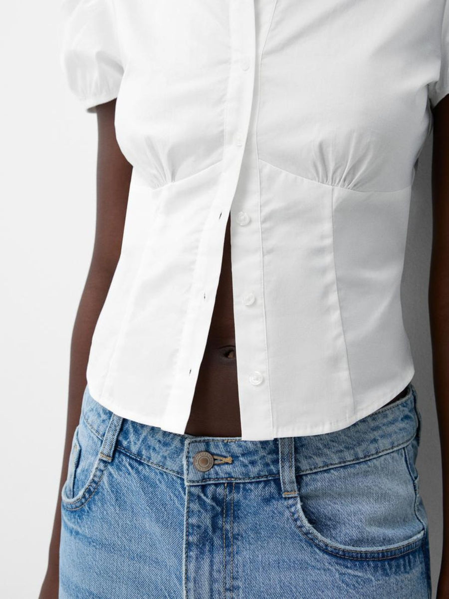 White shirt and blue jeans worn by a person on a plain background