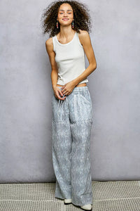 Woman wearing a white tank top and striped pants against a gray background