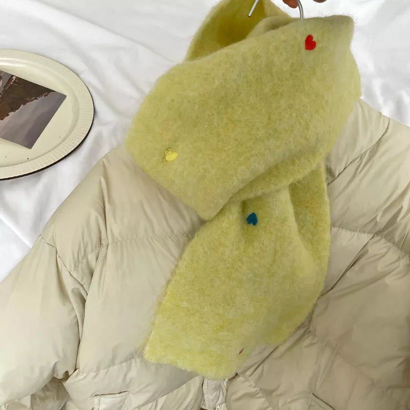 Light green scarf with colorful buttons on a beige puffer jacket against a white background