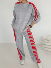 Person wearing a gray tracksuit with red stripes on a white background
