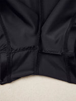 Close-up of a black jacket with a textured pattern on a beige surface