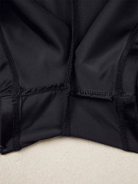 Close-up of a black jacket with a textured pattern on a beige surface
