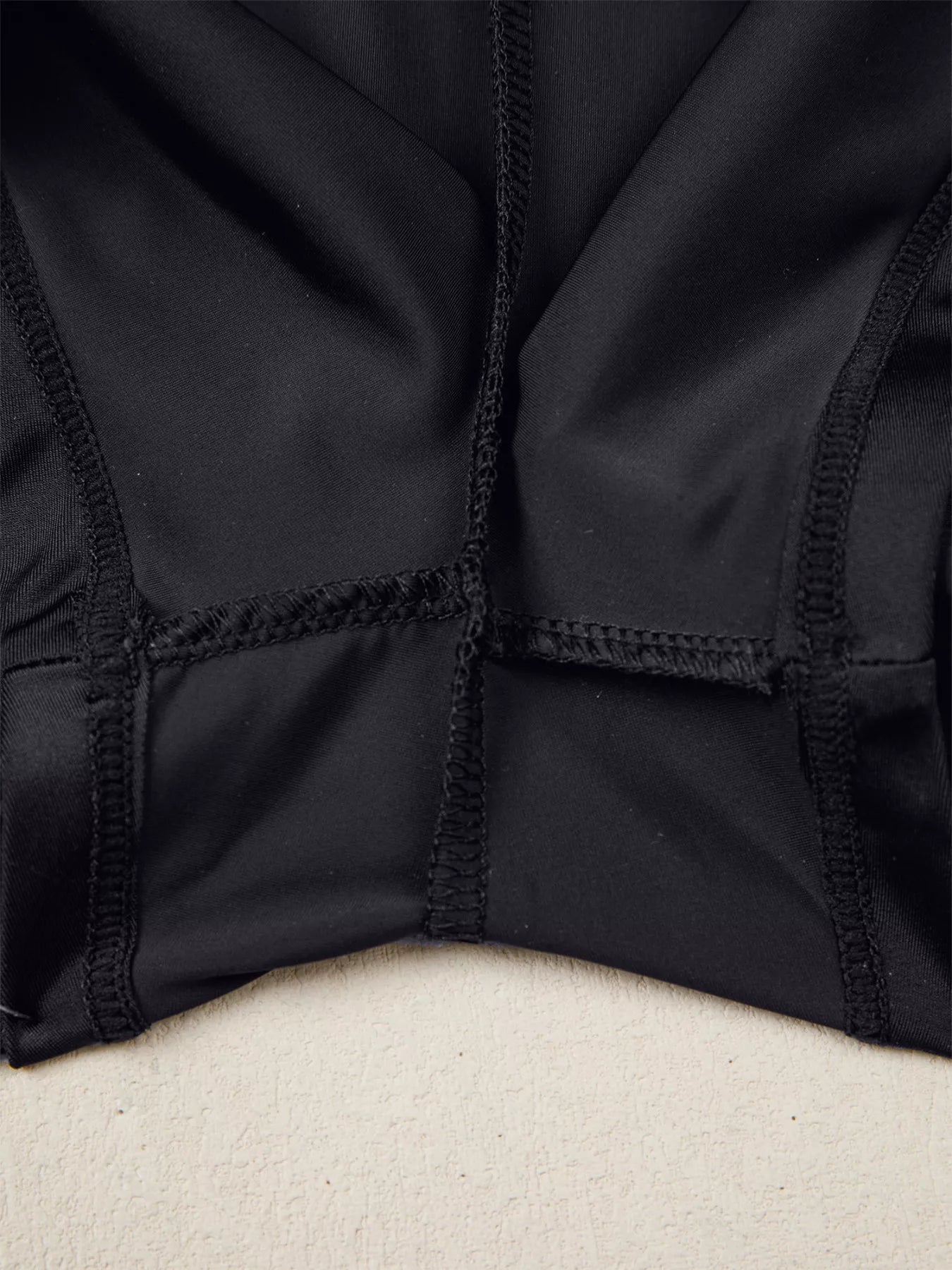 Close-up of a black jacket with a textured pattern on a beige surface