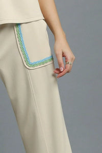 Beige pants with colorful trim on a gray background