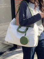 Person holding a white tote bag with a green handle and circular pouch.