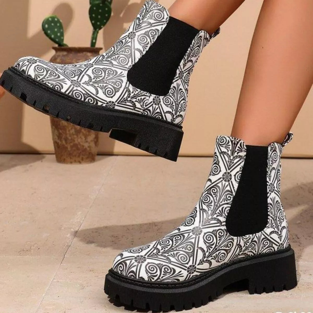 Black and white patterned boots with black socks on a neutral background