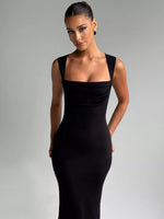 Woman wearing a black sleeveless dress against a gray background