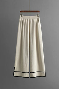 White wide-leg pants with black trim on a gray background