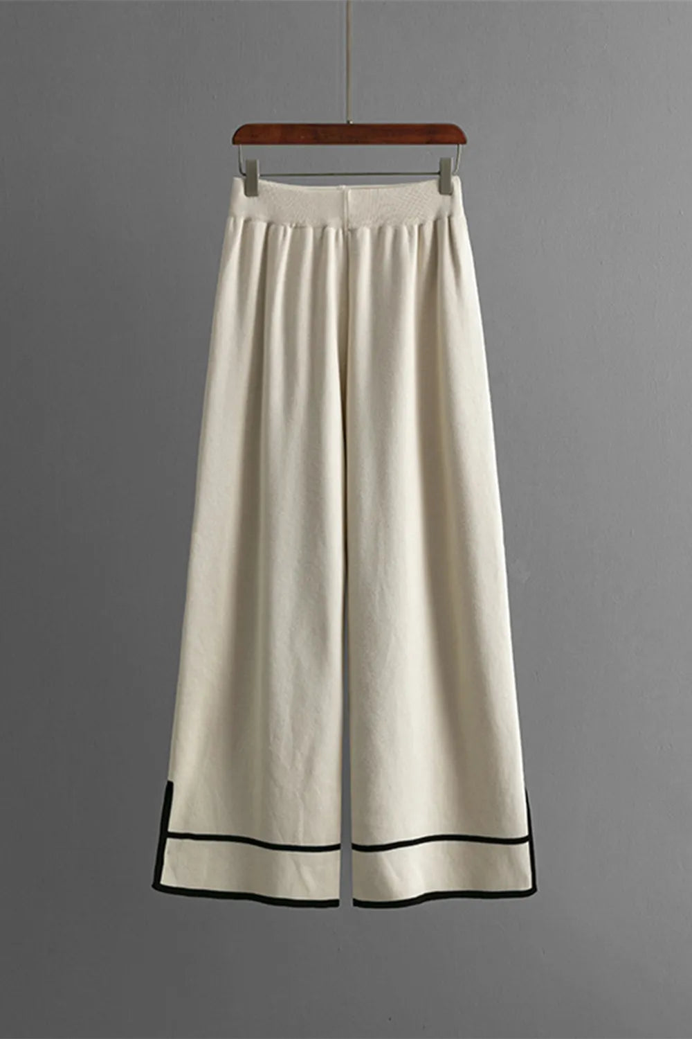 White wide-leg pants with black trim on a gray background