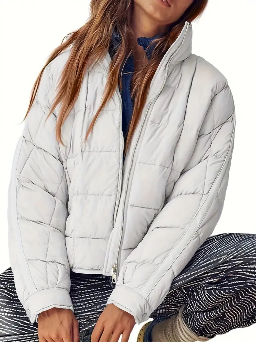 Person wearing a light gray puffer jacket on a white background