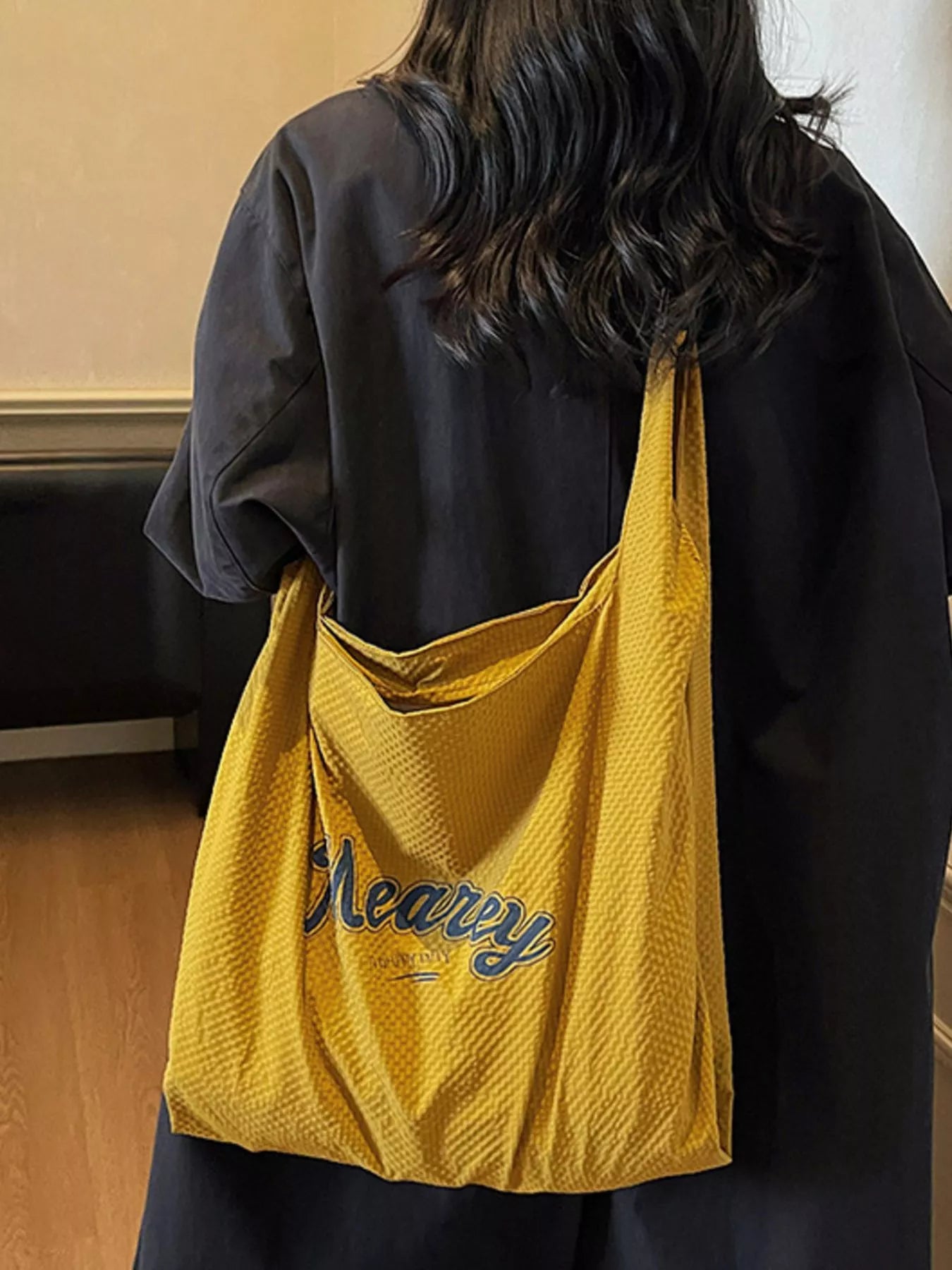 Person wearing a yellow bag with 'Heavy' text, standing indoors.