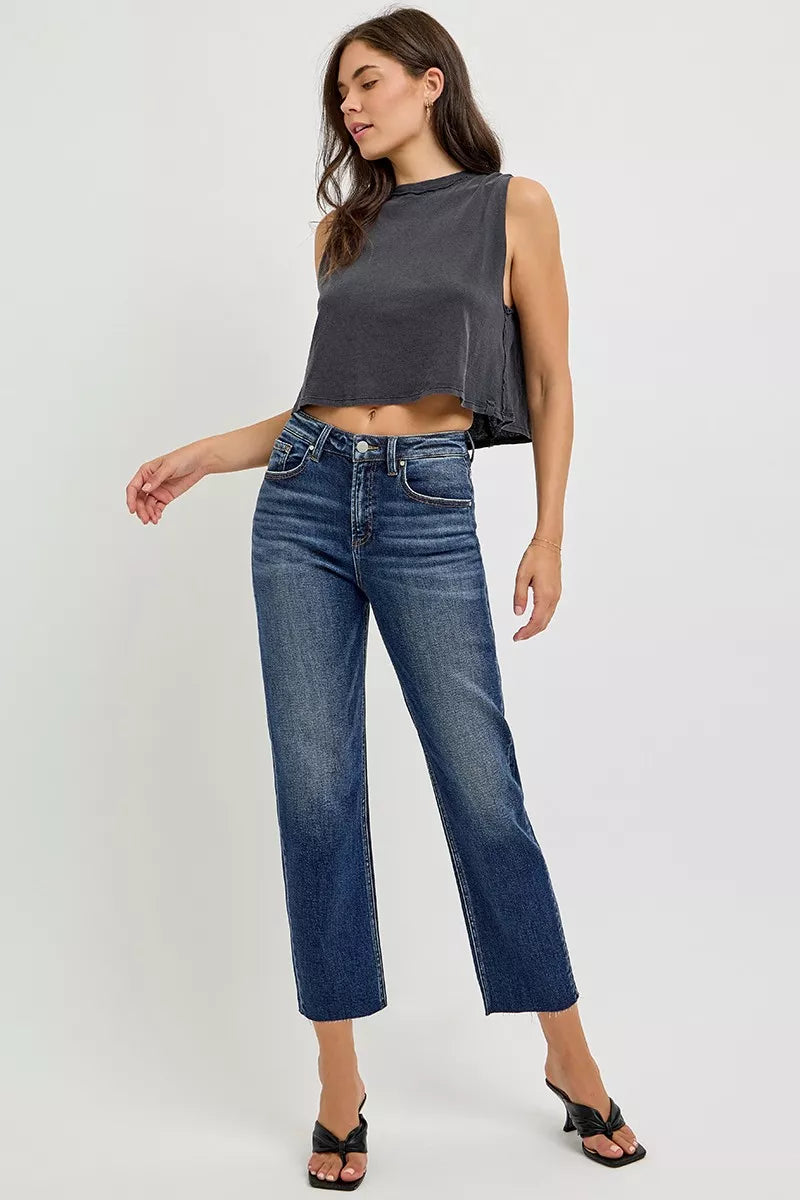 Woman wearing a dark gray sleeveless top and blue jeans on a white background