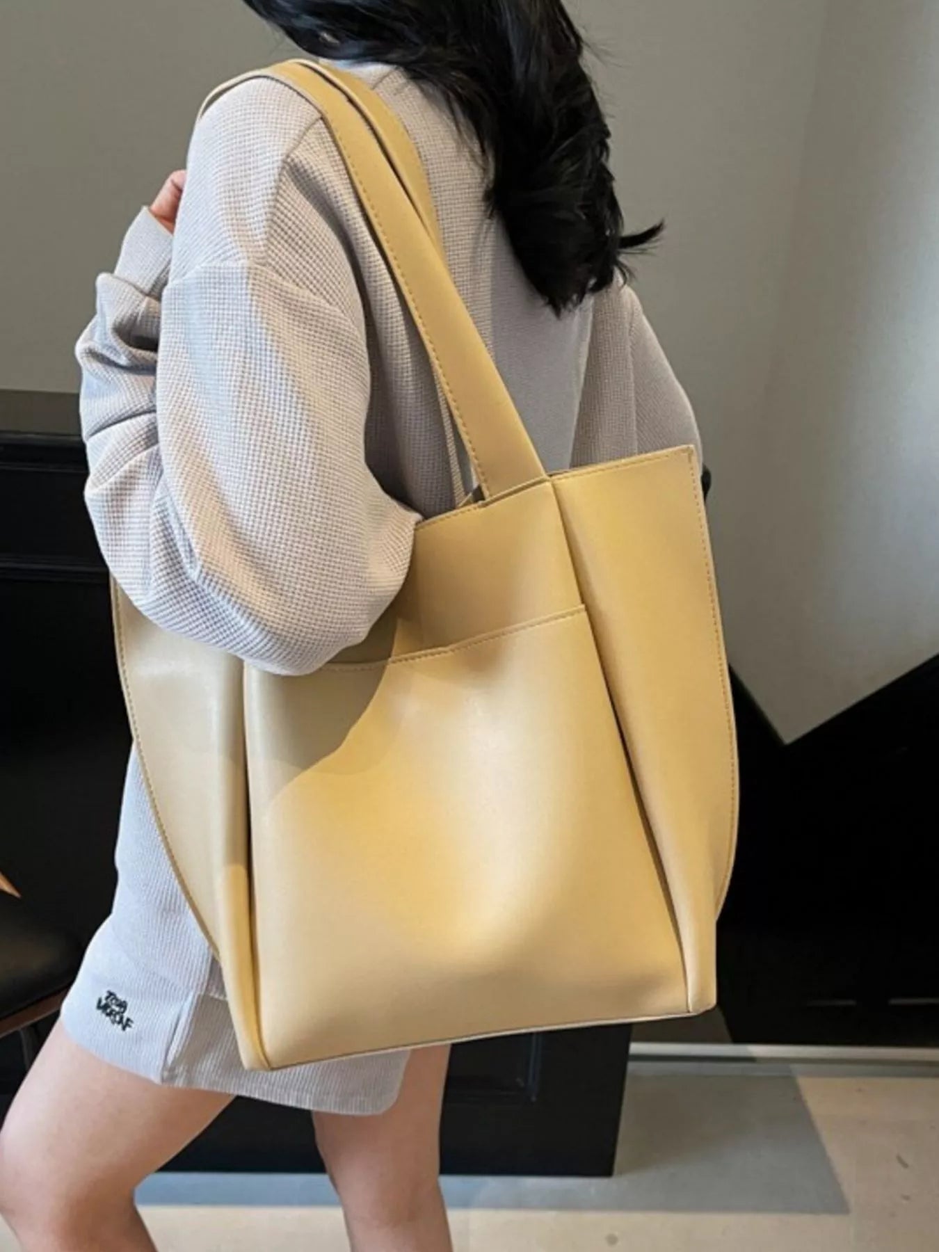 Person holding a yellow tote bag indoors