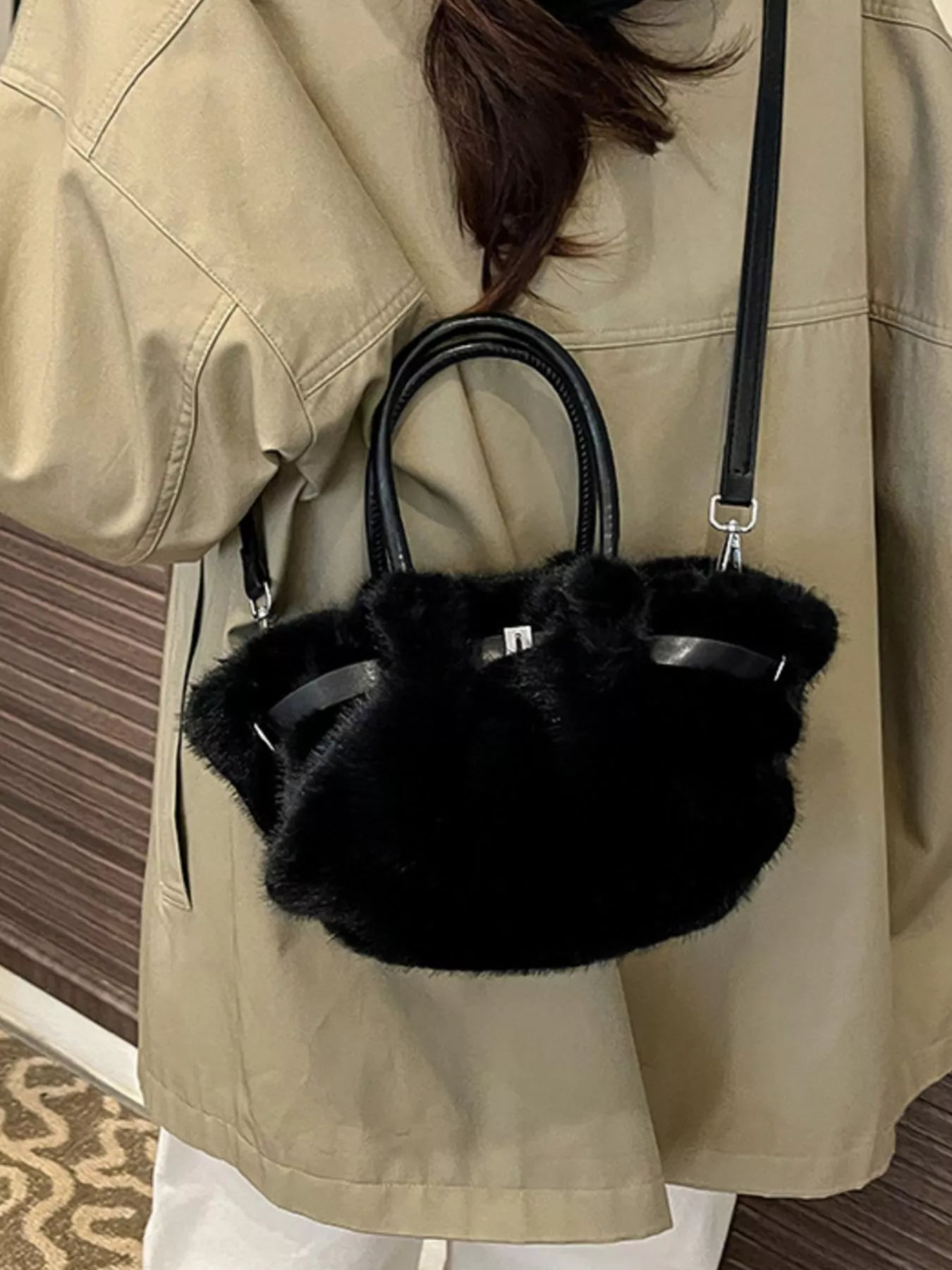 Person wearing a beige coat with a black furry handbag.